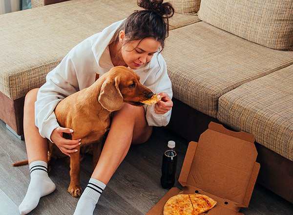 Femme donnant de la pizza à un chien